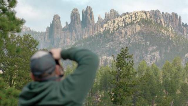 Visitor taking photograph of rock formations called "The Needles"
